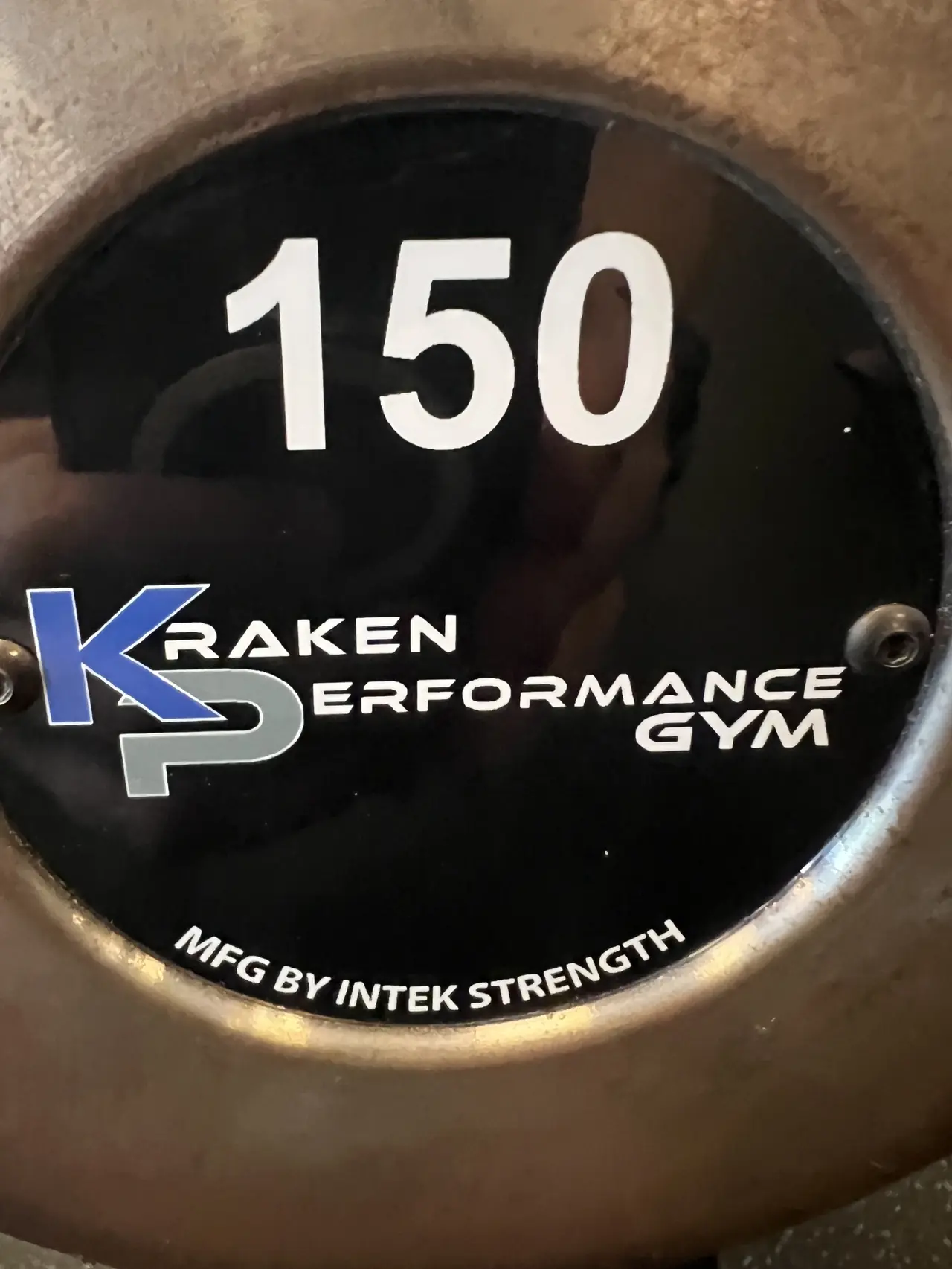 Close-up of a Kraken-branded 150 lb Intek Strength dumbbell end cap.